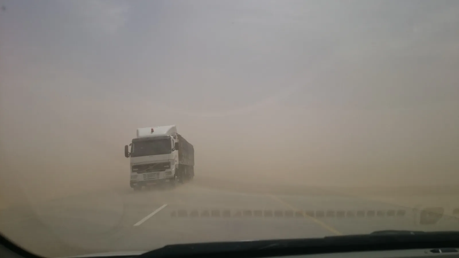 A hay truck driving through a dust storm near Haima, Oman